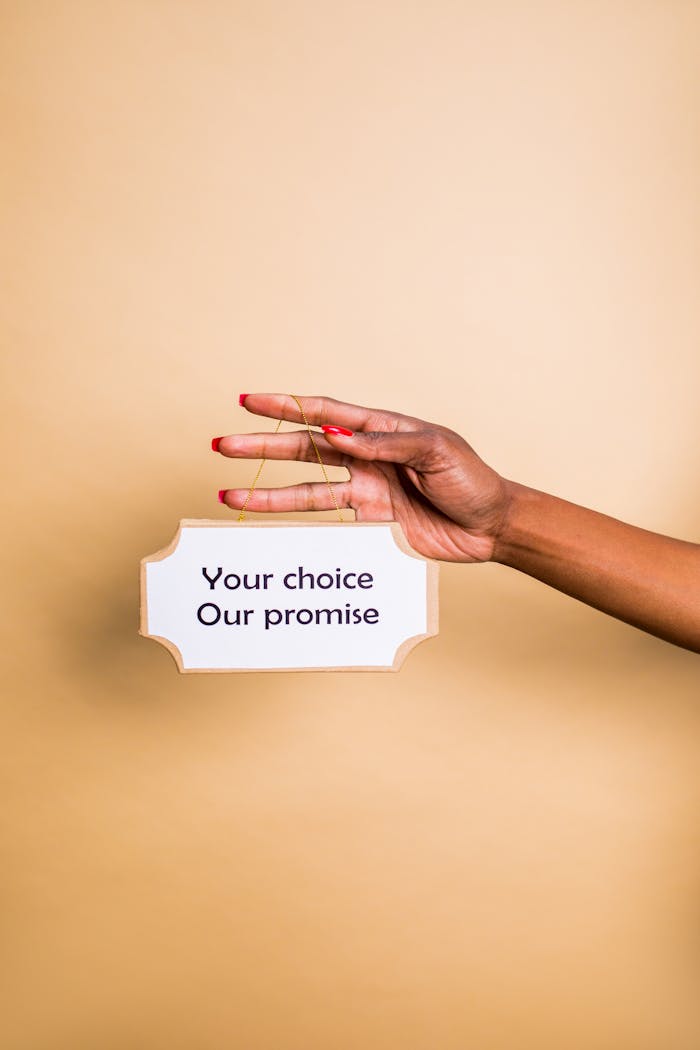 A hand holding a sign with the message 'Your choice, Our promise' on a neutral background.